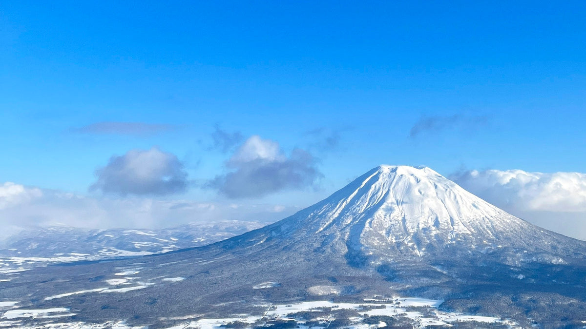 青空の下、雪をかぶった羊蹄山と雪原の風景
